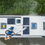 Man Pressure Washing RV Camper Van Roof Equipped with Solar Pane