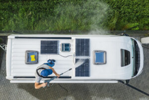 Man Pressure Washing RV Camper Van Roof Equipped with Solar Pane