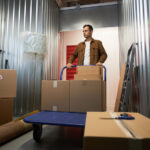 Pensive man pushing cart with belongings inside storage unit