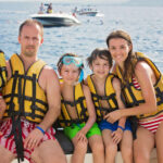 Happy family with life vests, safely spending time on their boat.