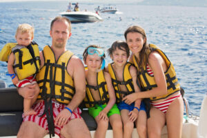 Happy family with life vests, safely spending time on their boat.