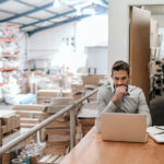 Manager working while sitting in an overcrowded warehouse office
