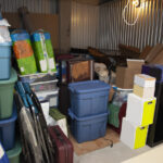 Interior of a self storage unit in a warehouse filled to the brim with belongings and junk