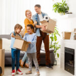 Family with cardboard boxes standing in row at home