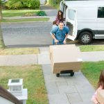 Children helping parents unload boxes from van on family moving in day